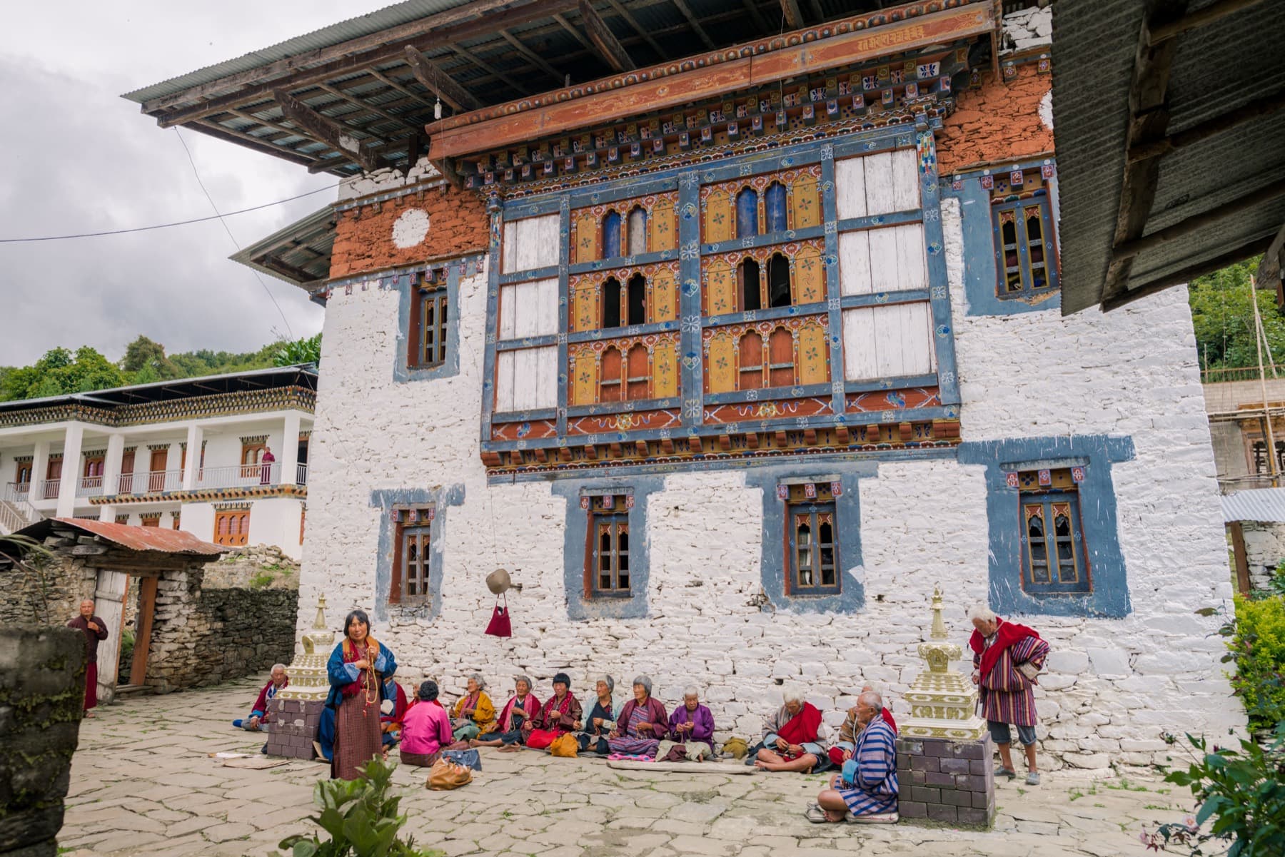 The whitewashed stone façade of Rephel Mebar Lhakhang (Sangchen Ogyen Tsuklag) with ornately painted Bhutanese window frames.
